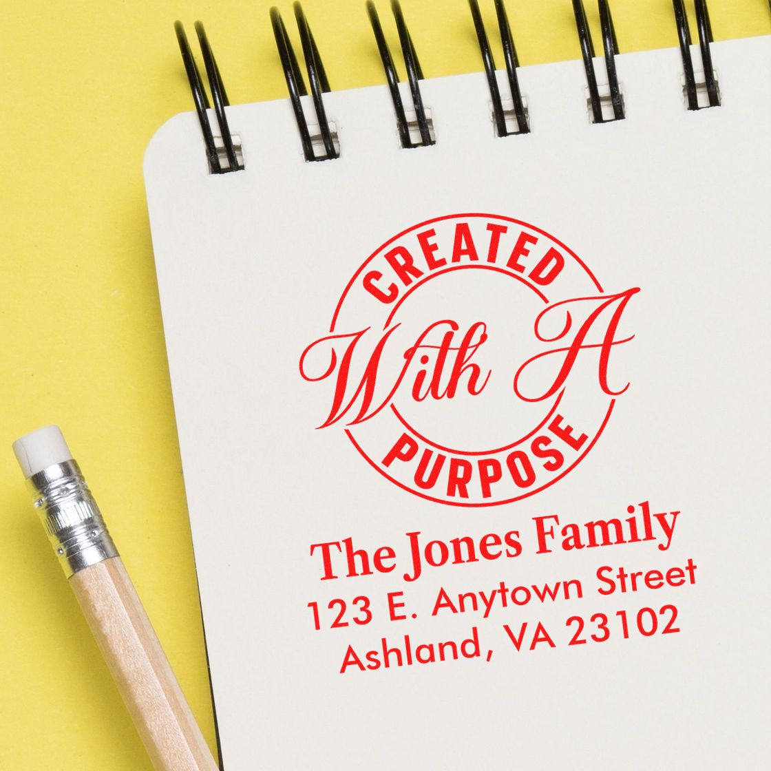 Custom address rubber stamp reading Created With A Purpose with family name on notebook for personalized stationery and branding.