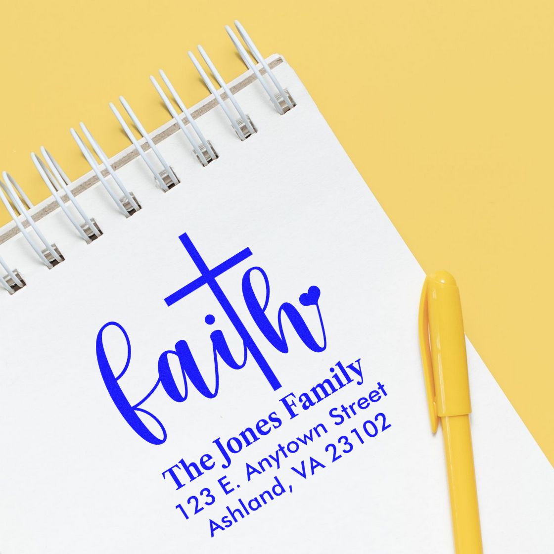 Custom faith family address rubber stamp design on notebook, featuring blue script logo and return address text.