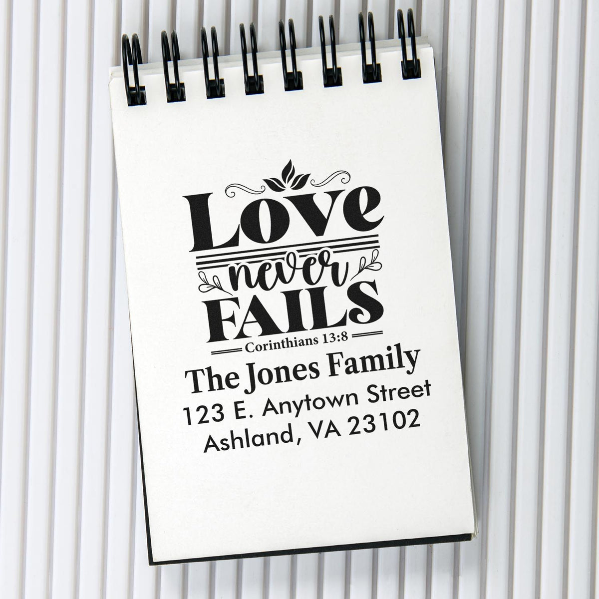 Custom rubber stamp with Bible verse Love never fails and personalized family return address for Christian stationery.