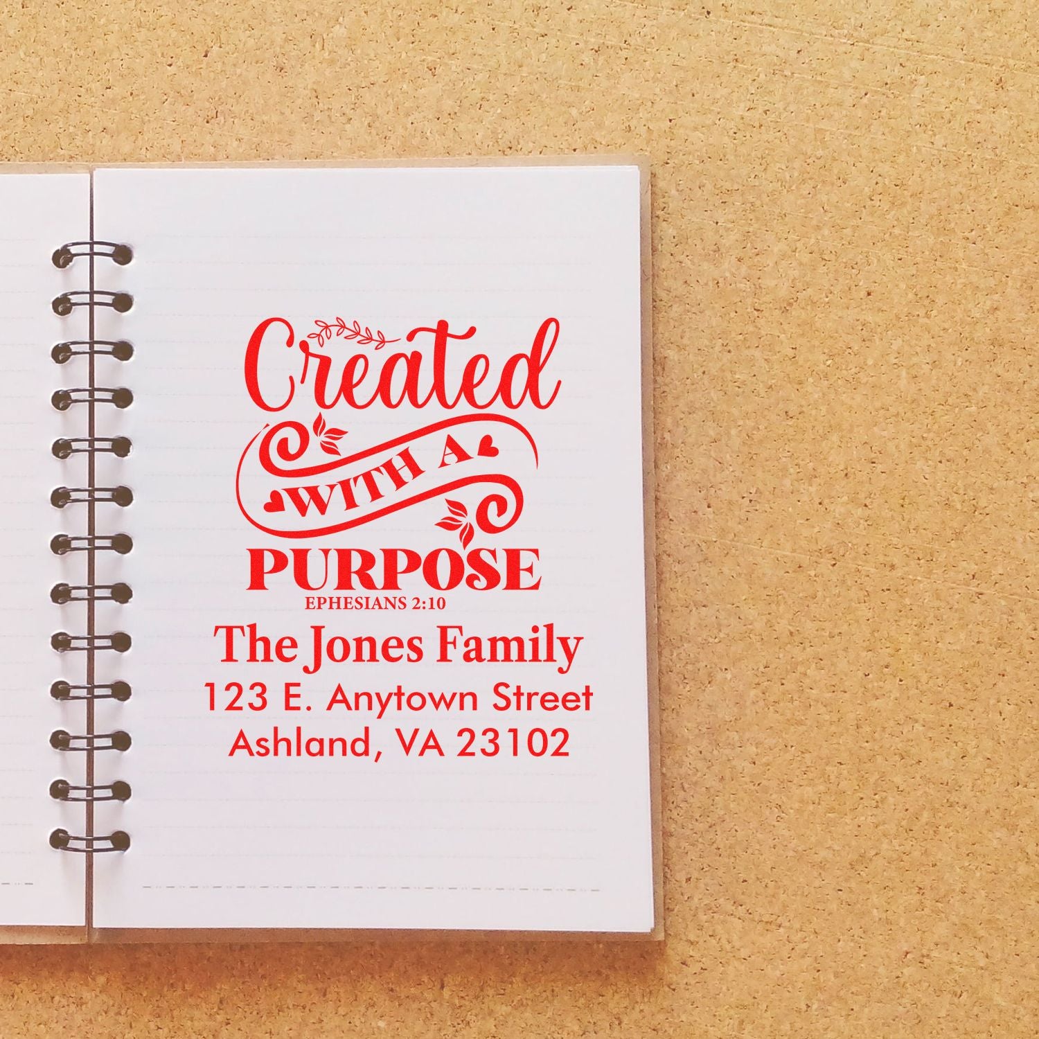 Custom faith-based rubber stamp on notebook with Created with a Purpose, family name, address, and Ephesians 2:10.