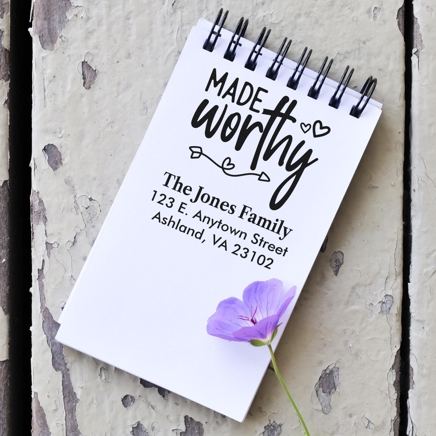 Custom return address rubber stamp with Made worthy design and family address on a notebook
