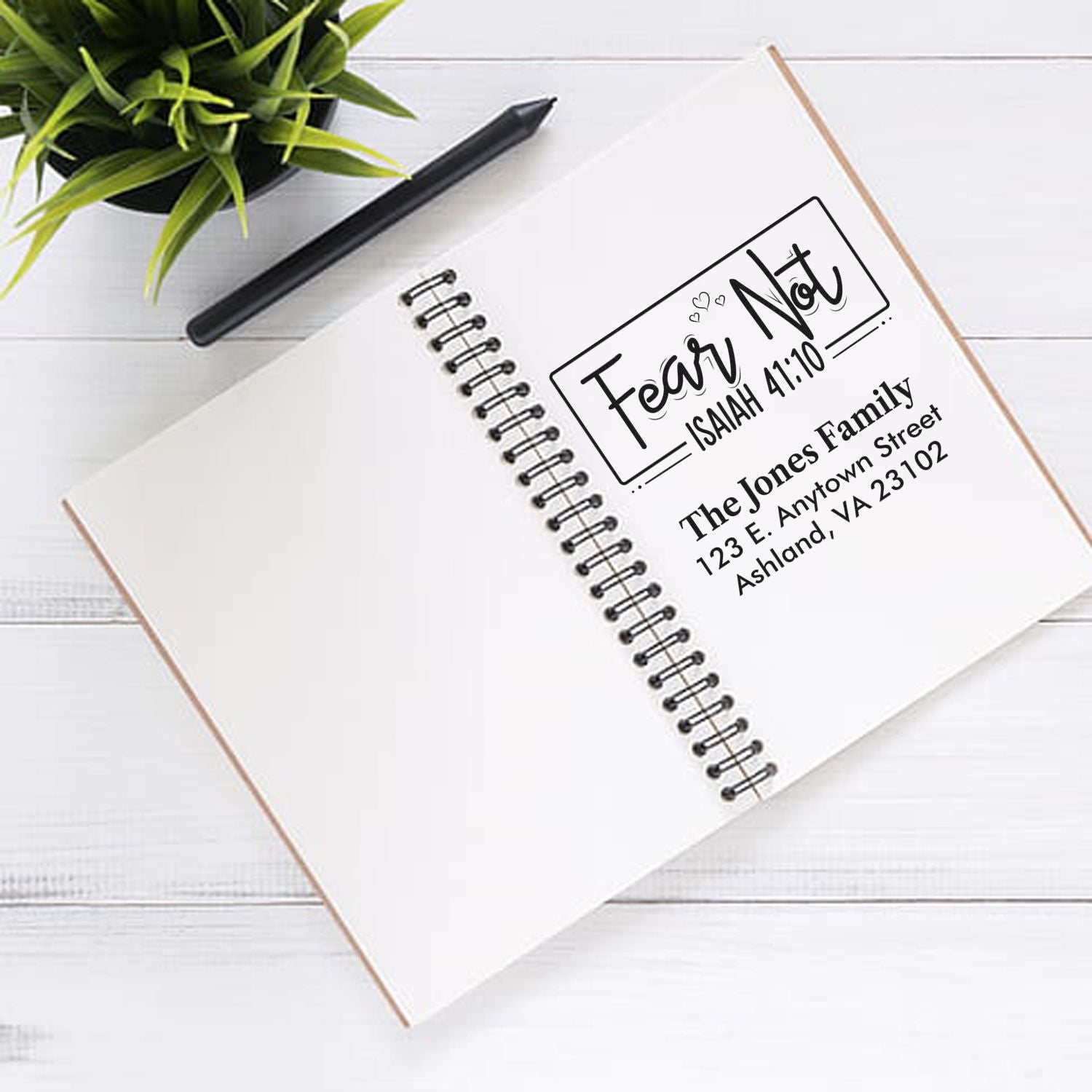 Custom faith-based rubber stamp with Fear Not Isaiah 41:10 and personalized family address on a notebook.