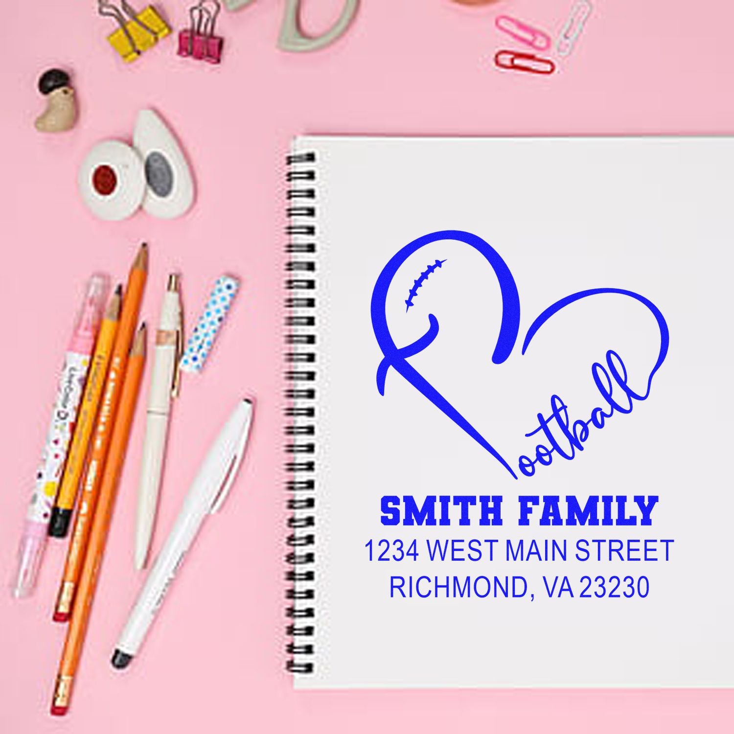 Custom return address rubber stamp with football heart design and Smith Family address on a notebook.