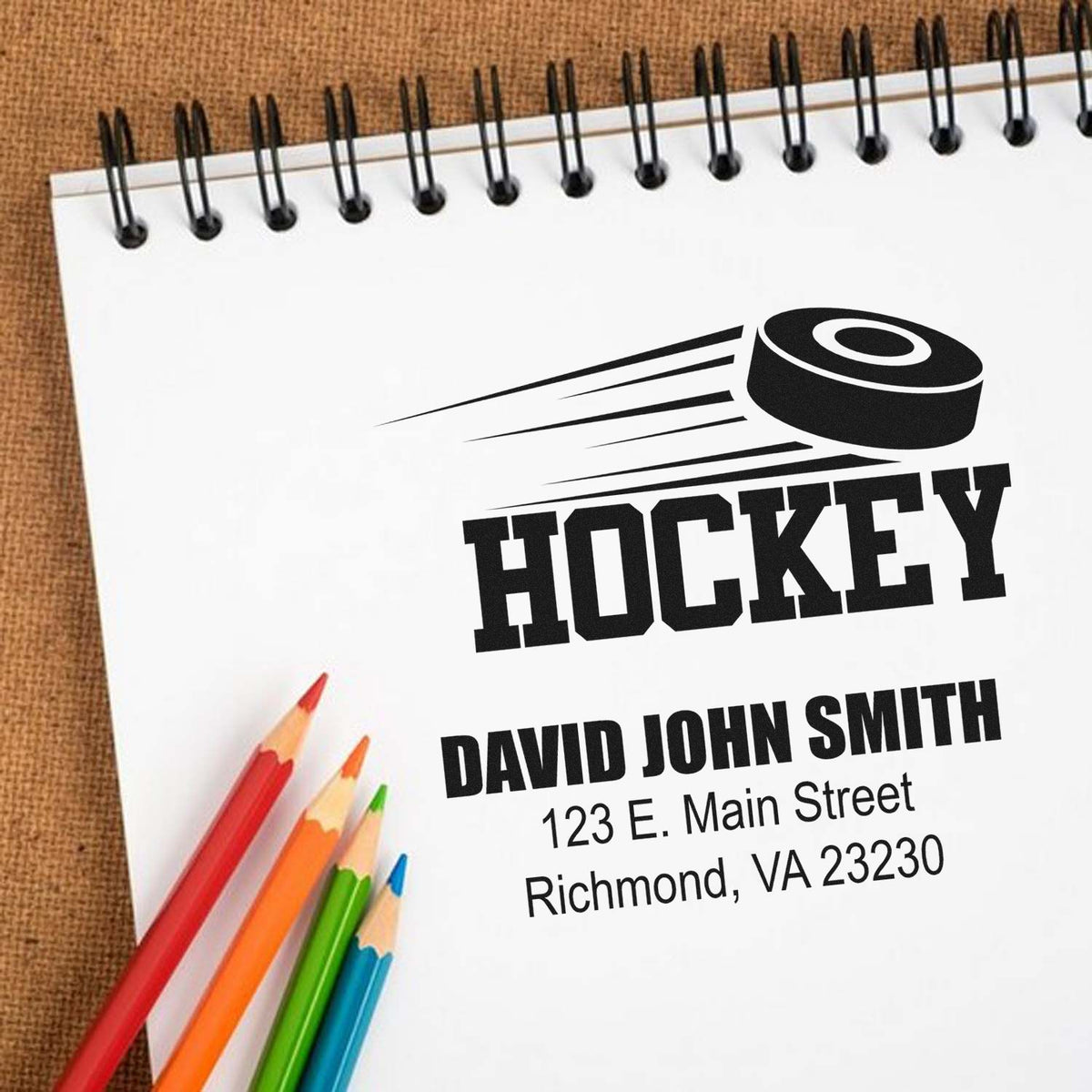 Custom hockey rubber stamp mockup with personalized name and address on a notepad.