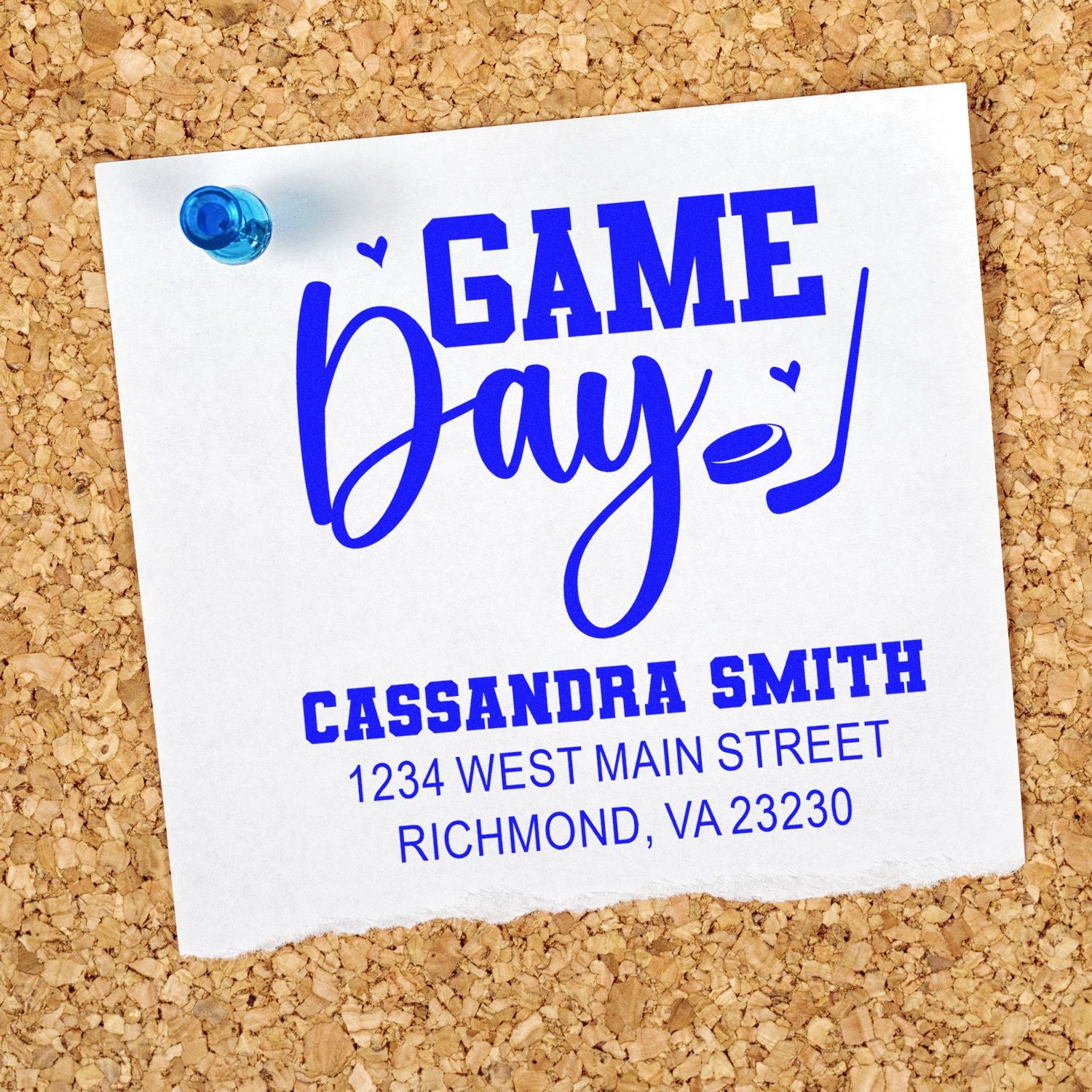Custom Game Day rubber stamp design with name and address in blue ink, pinned to corkboard for event branding.