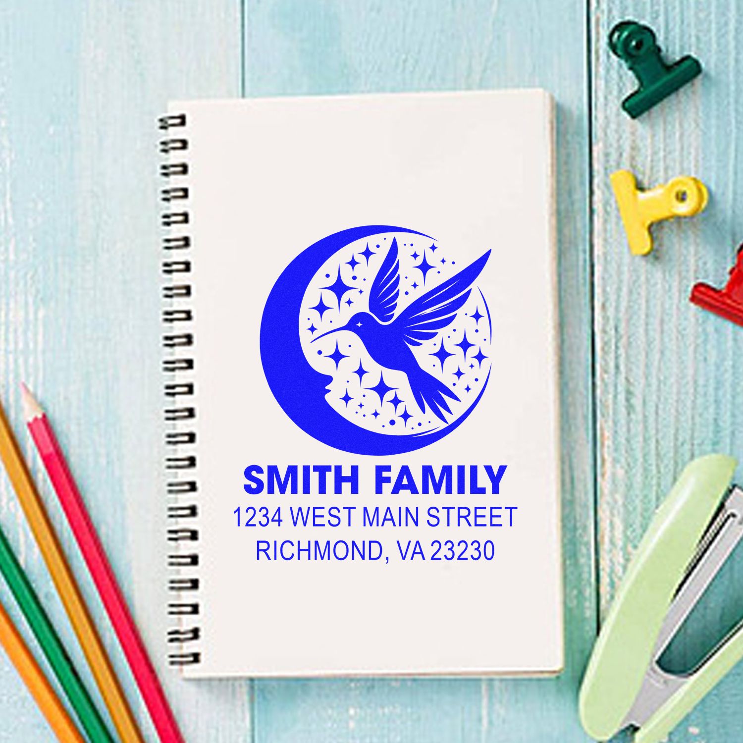 Personalized address rubber stamp with hummingbird moon logo for Smith Family on notebook.
