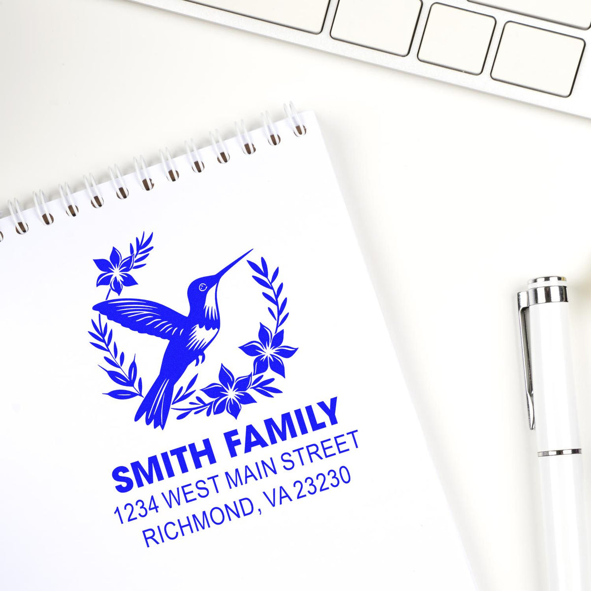 Custom rubber stamp with hummingbird design and Smith Family return address on a notebook, ideal for personalized mail.
