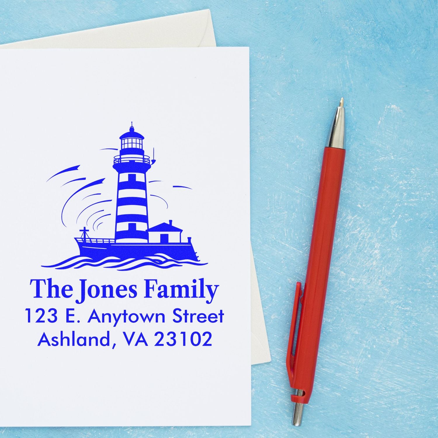 Custom lighthouse return address rubber stamp for The Jones Family on stationery, with red pen beside it.