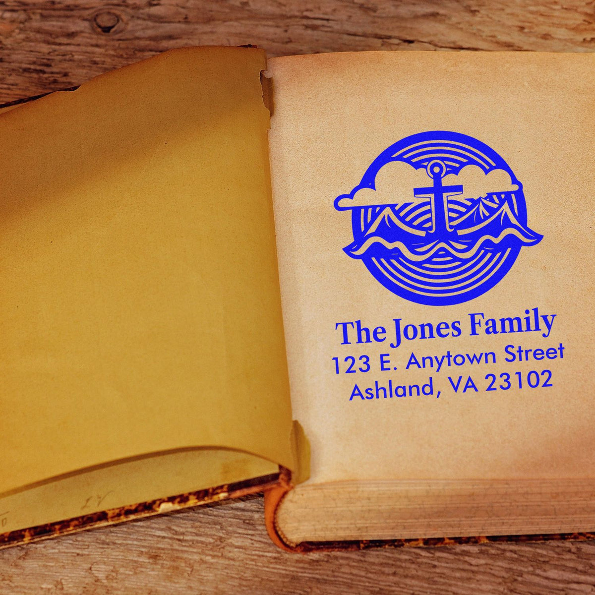 Personalized address rubber stamp imprint on book pages with family name, address, and blue nautical logo.