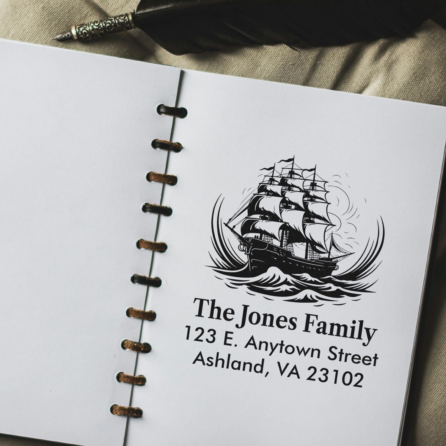 Personalized rubber address stamp with sailing ship design and The Jones Family address in a notebook.