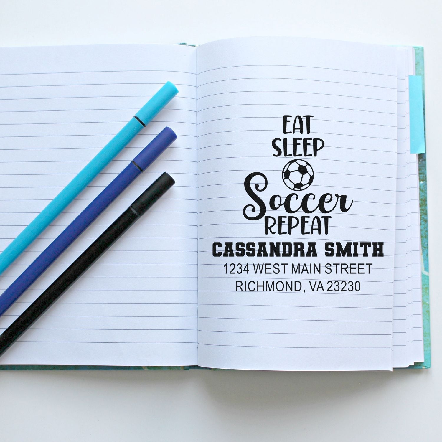 Custom soccer rubber stamp with Eat Sleep Soccer Repeat design and personalized name and address on a notebook.
