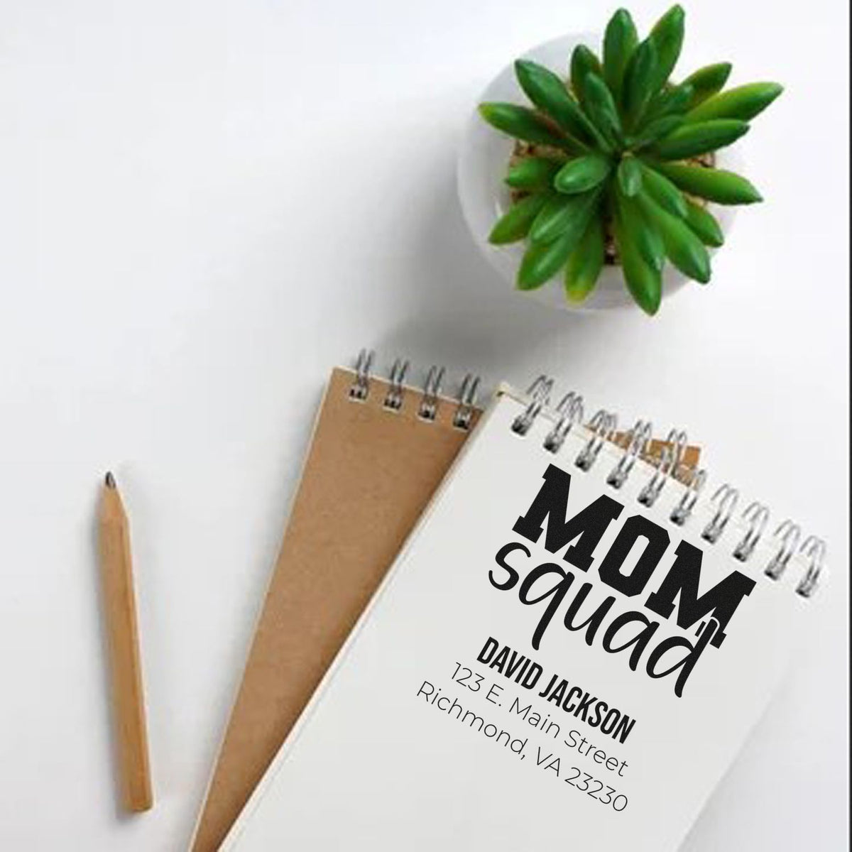 Personalized rubber address stamp for Mom Squad, featuring name and return address on a notebook