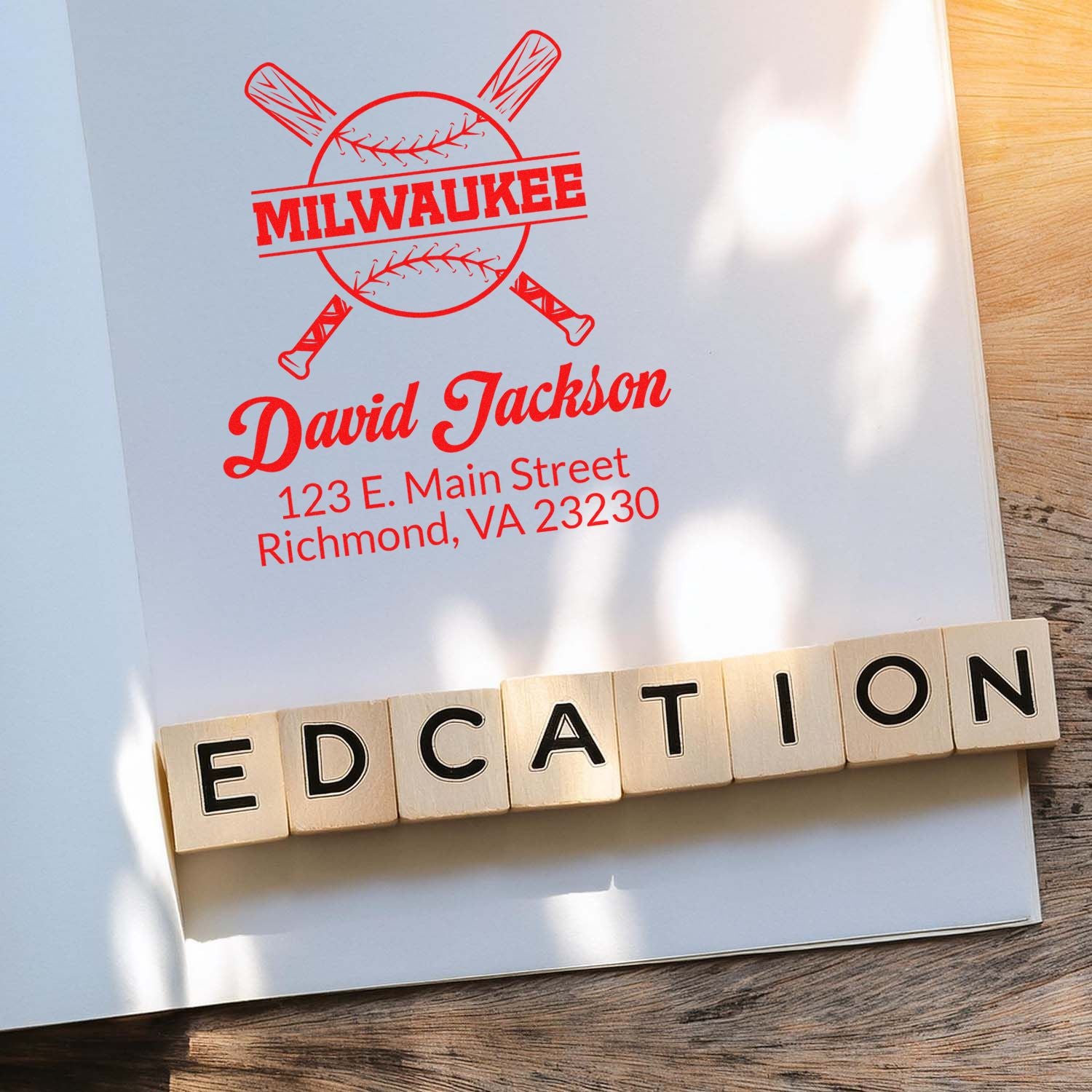 Custom rubber stamp design with baseball logo, name, and address, shown with wooden letter stamps spelling EDUCATION.