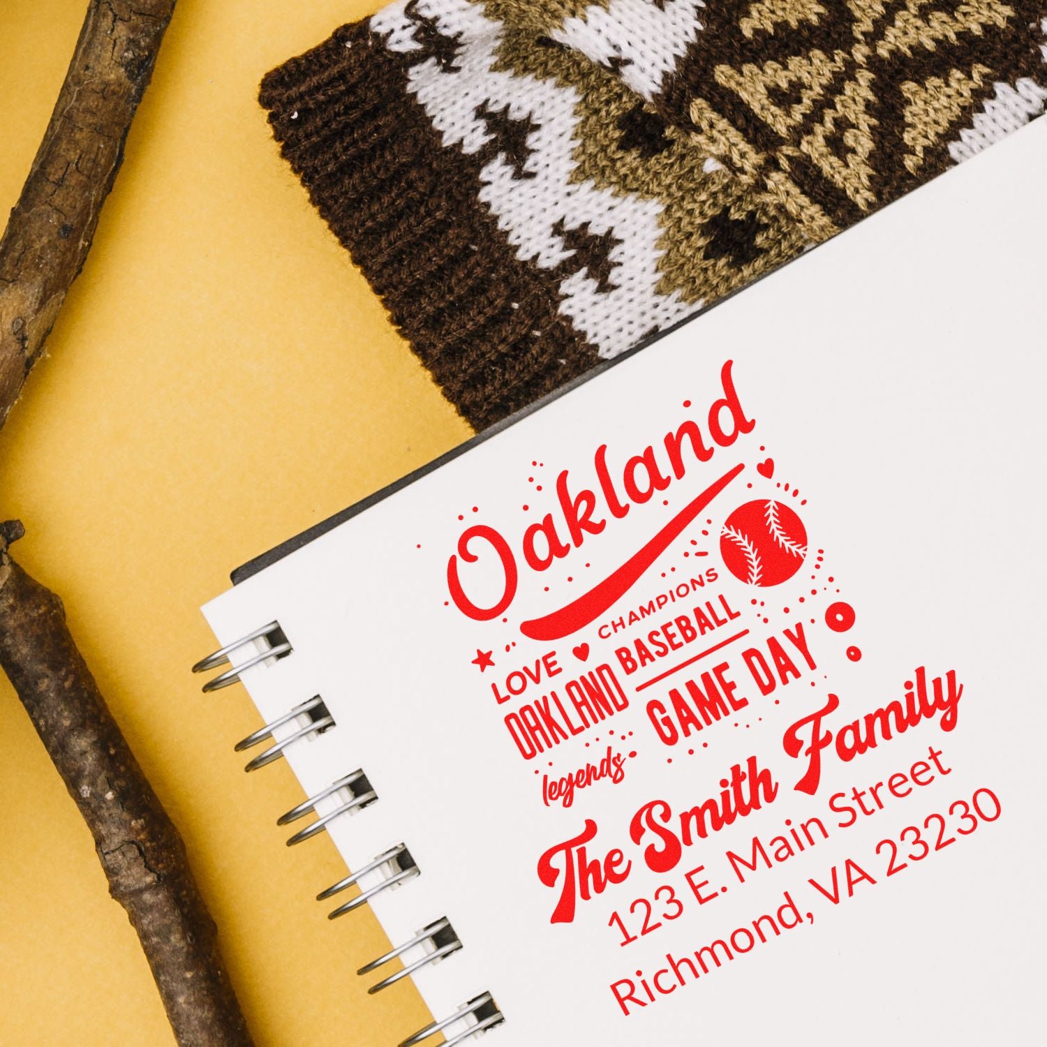 Personalized Oakland baseball family address rubber stamp impression in red on a notebook.