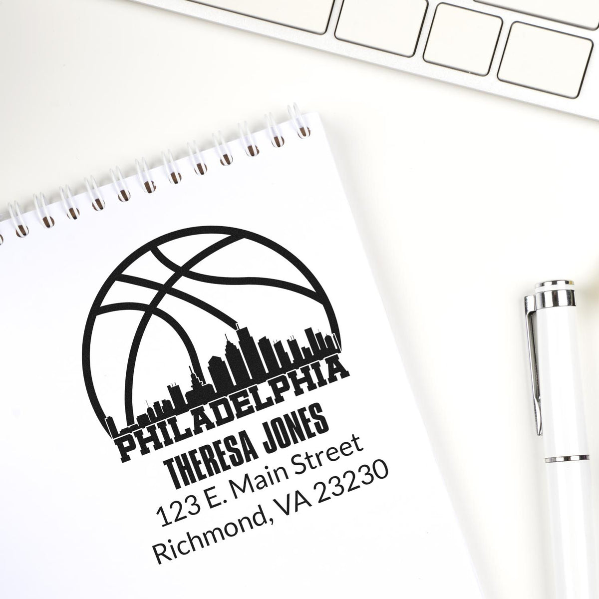 Custom rubber address stamp with Philadelphia skyline logo, stamped on a notebook with Theresa Jones address for business stationery.