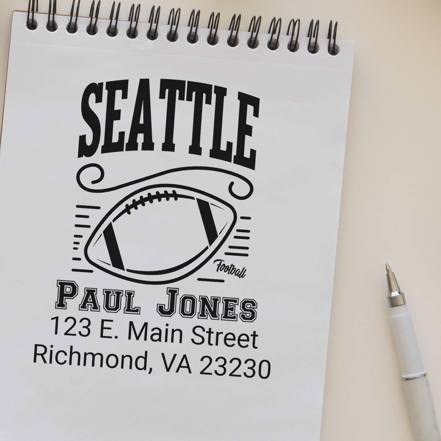 Custom Seattle football rubber stamp design with name Paul Jones and Richmond, VA address on a notebook proof.