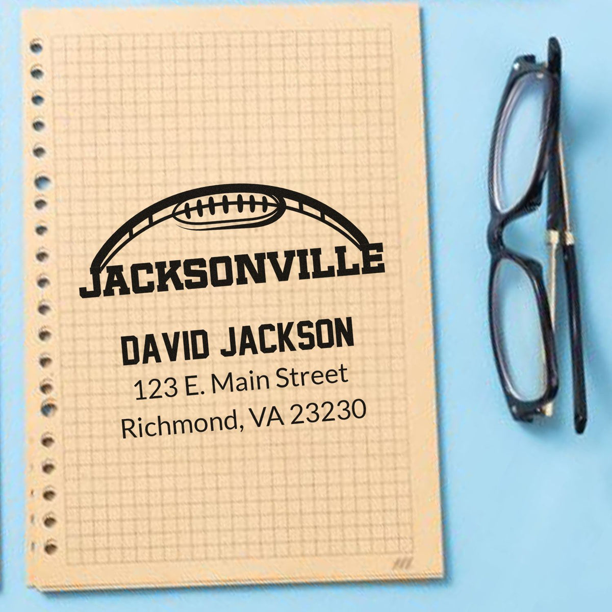 Personalized rubber stamp impression with football logo, Jacksonville name, and Richmond address on notebook.