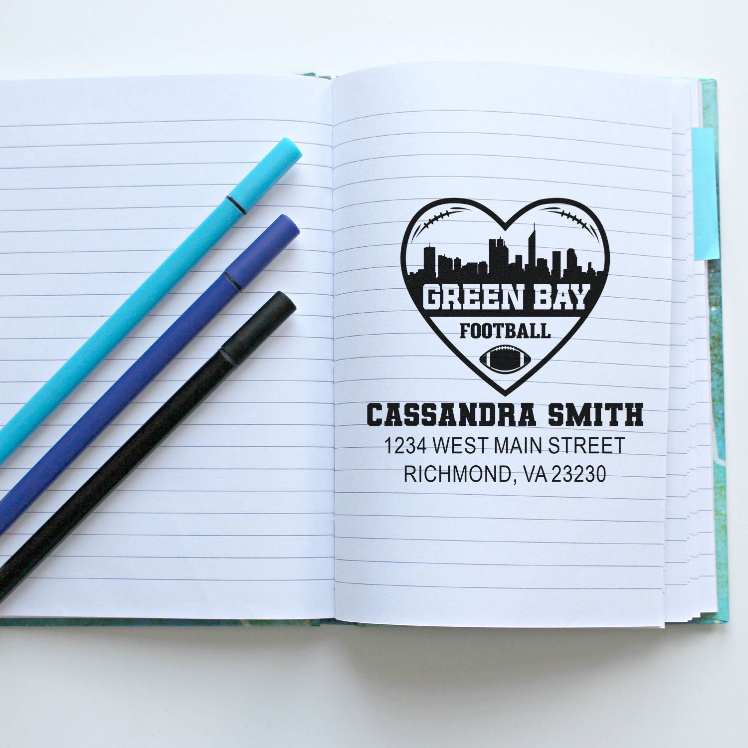 Custom Green Bay football return address rubber stamp with personalized name and address, stamped on notebook paper.