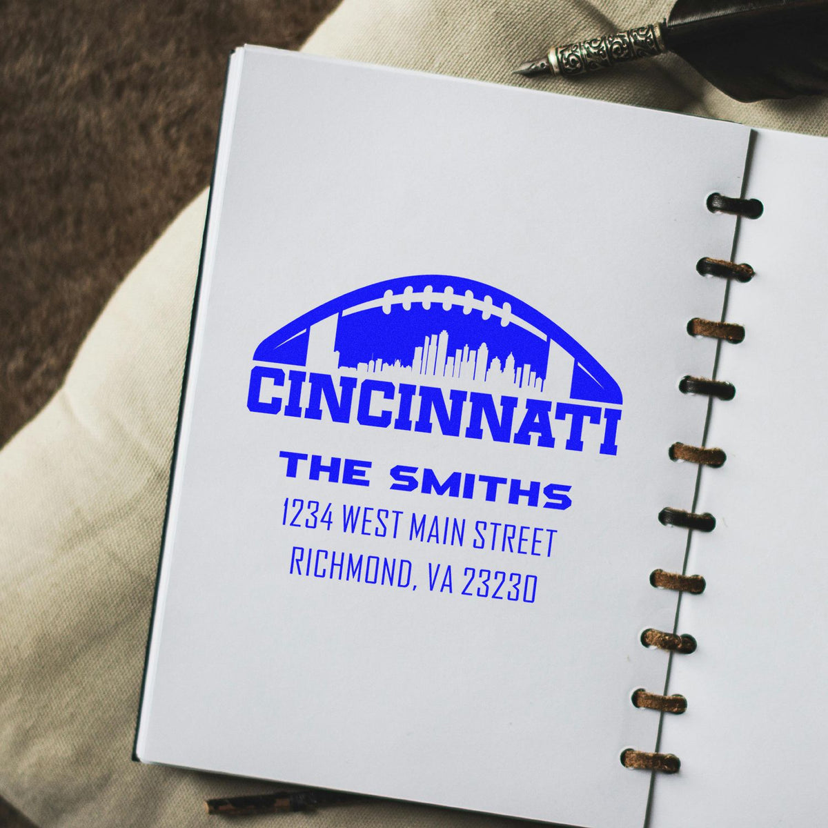 Personalized rubber stamp imprint with Cincinnati football logo, The Smiths, and Richmond, VA address on a notebook page.