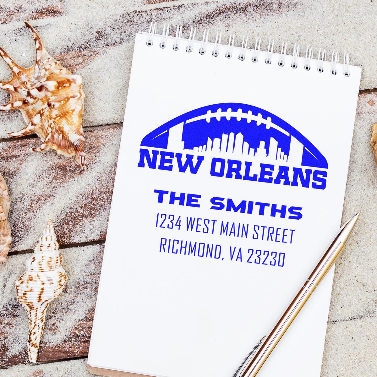 Custom rubber address stamp with New Orleans skyline football logo, family name, and address on a notebook.