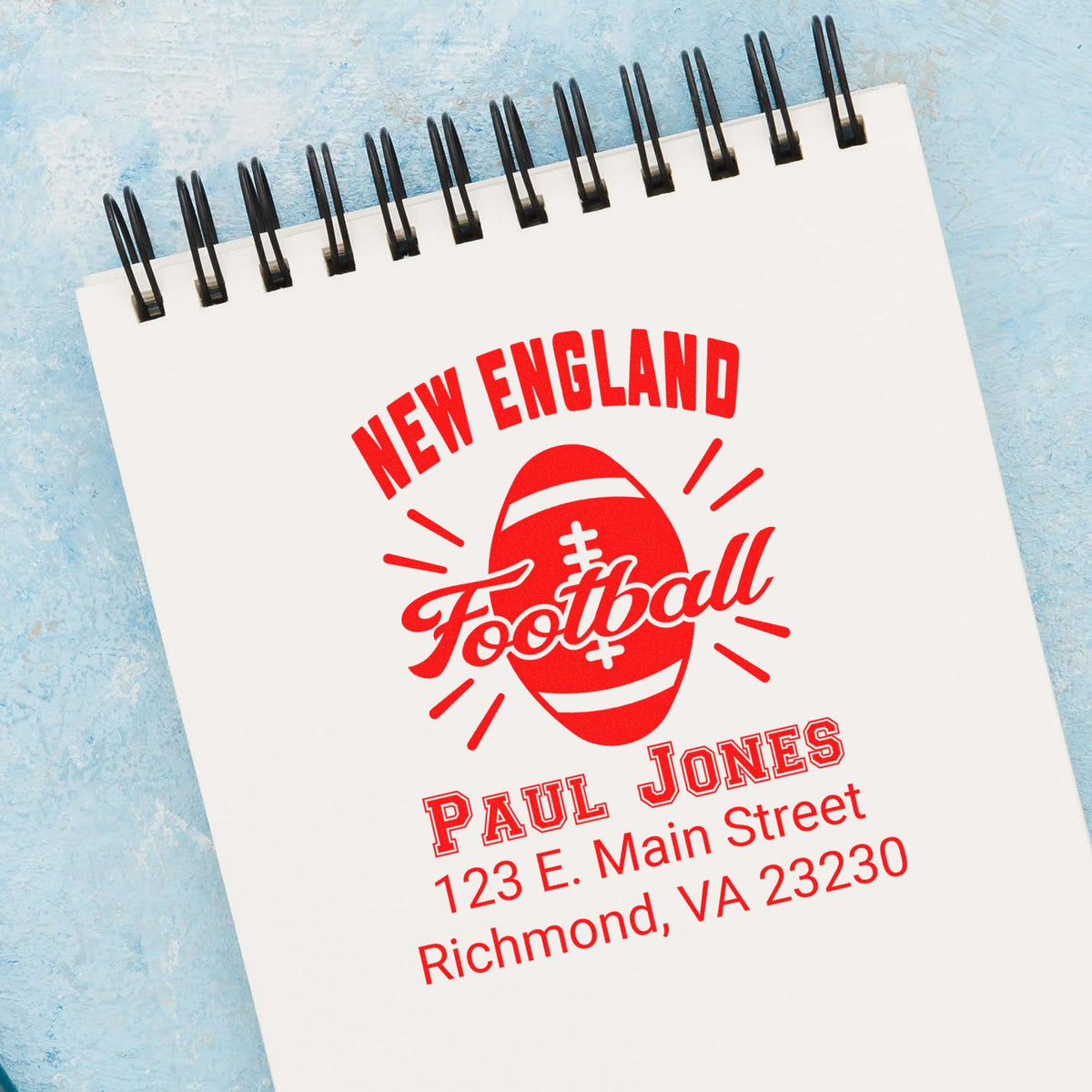 Custom New England Football rubber stamp design with name and return address on a spiral notebook.