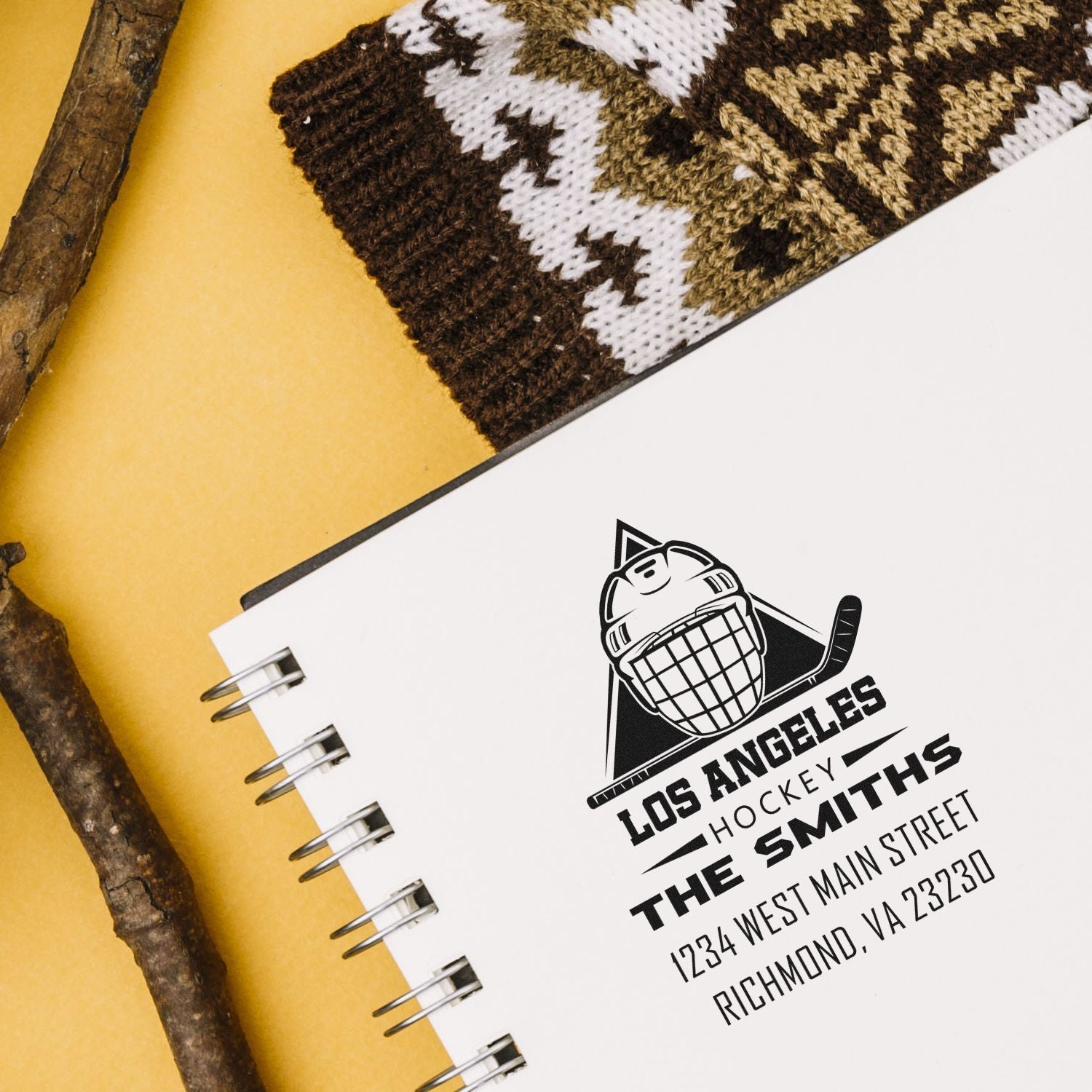 Personalized hockey rubber stamp with Los Angeles team logo, family name, and return address on a notebook.