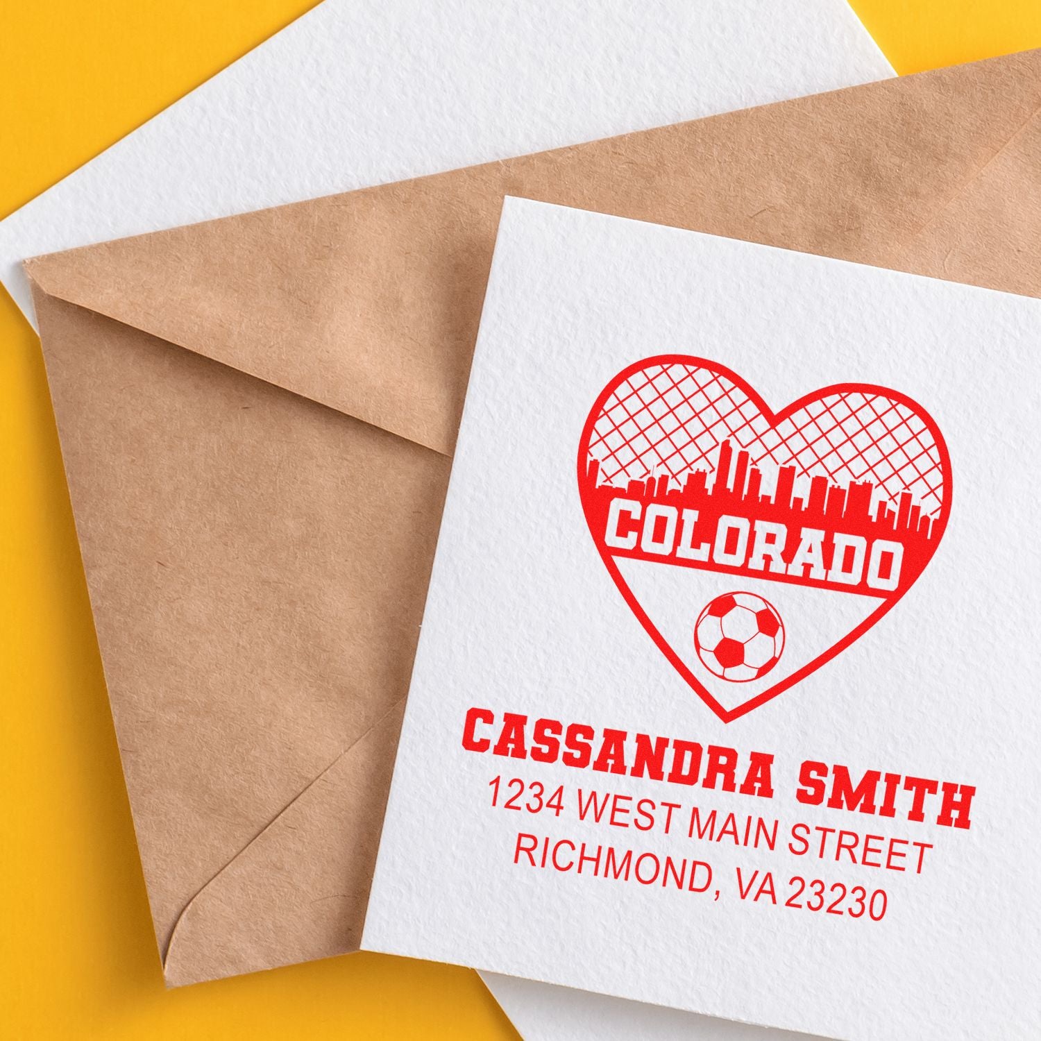 Custom rubber stamp on envelope featuring a Colorado heart logo, soccer icon, and personalized return address.