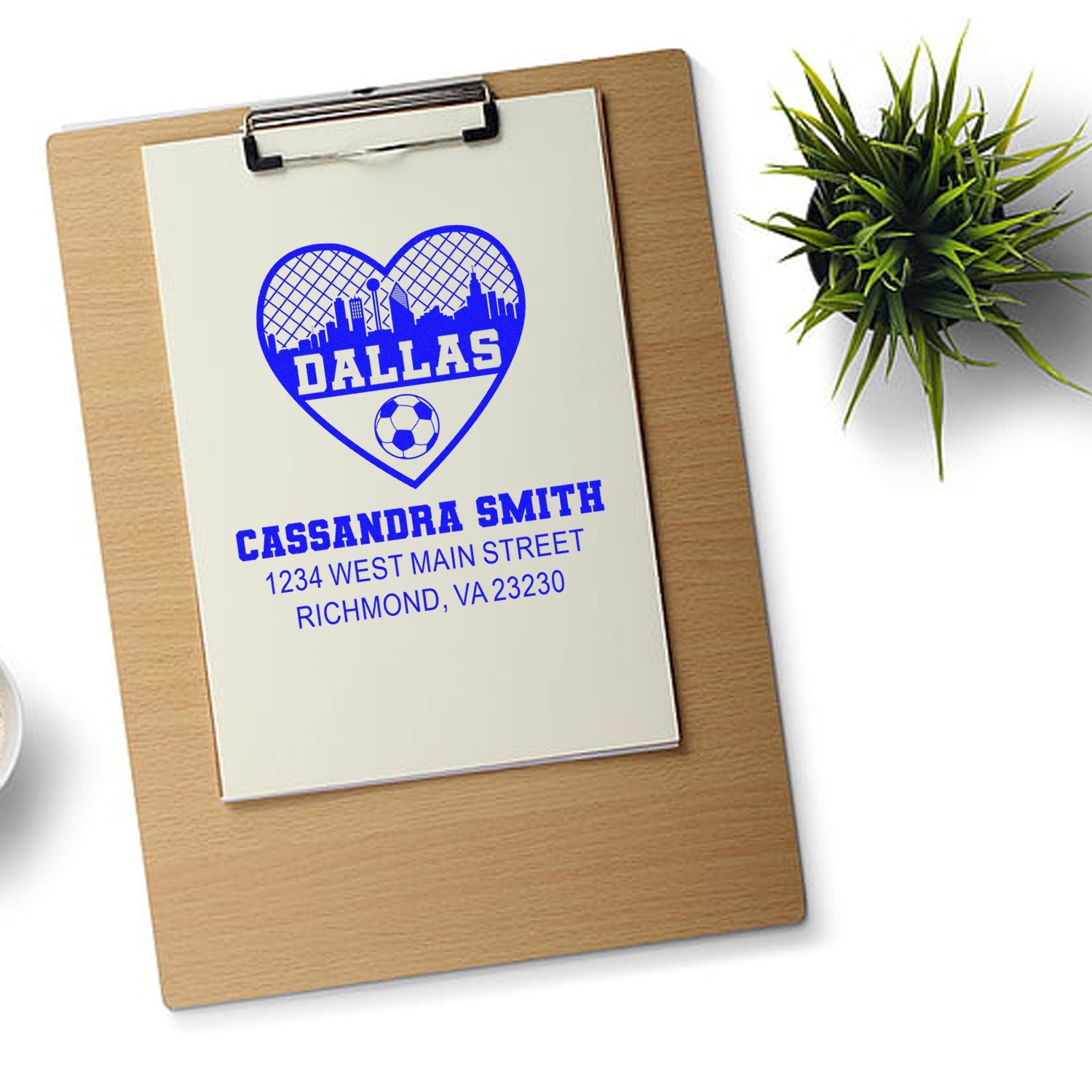 Custom return address rubber stamp with Dallas skyline heart, soccer ball, and Cassandra Smith details on clipboard mockup.