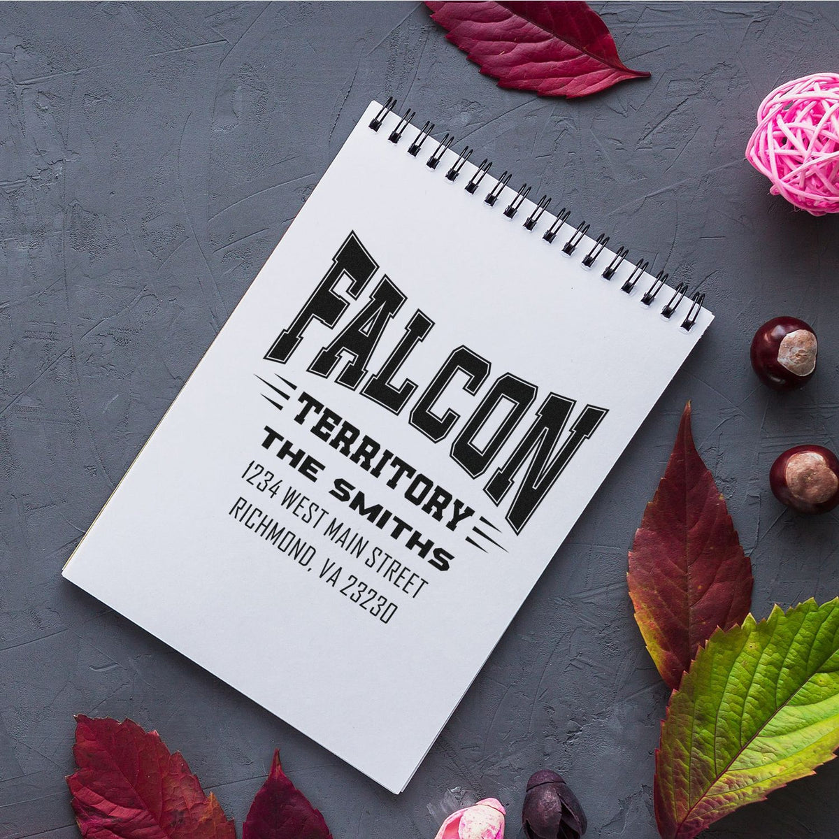 Custom rubber address stamp sample with bold FALCON TERRITORY branding and Richmond, VA business address on notebook