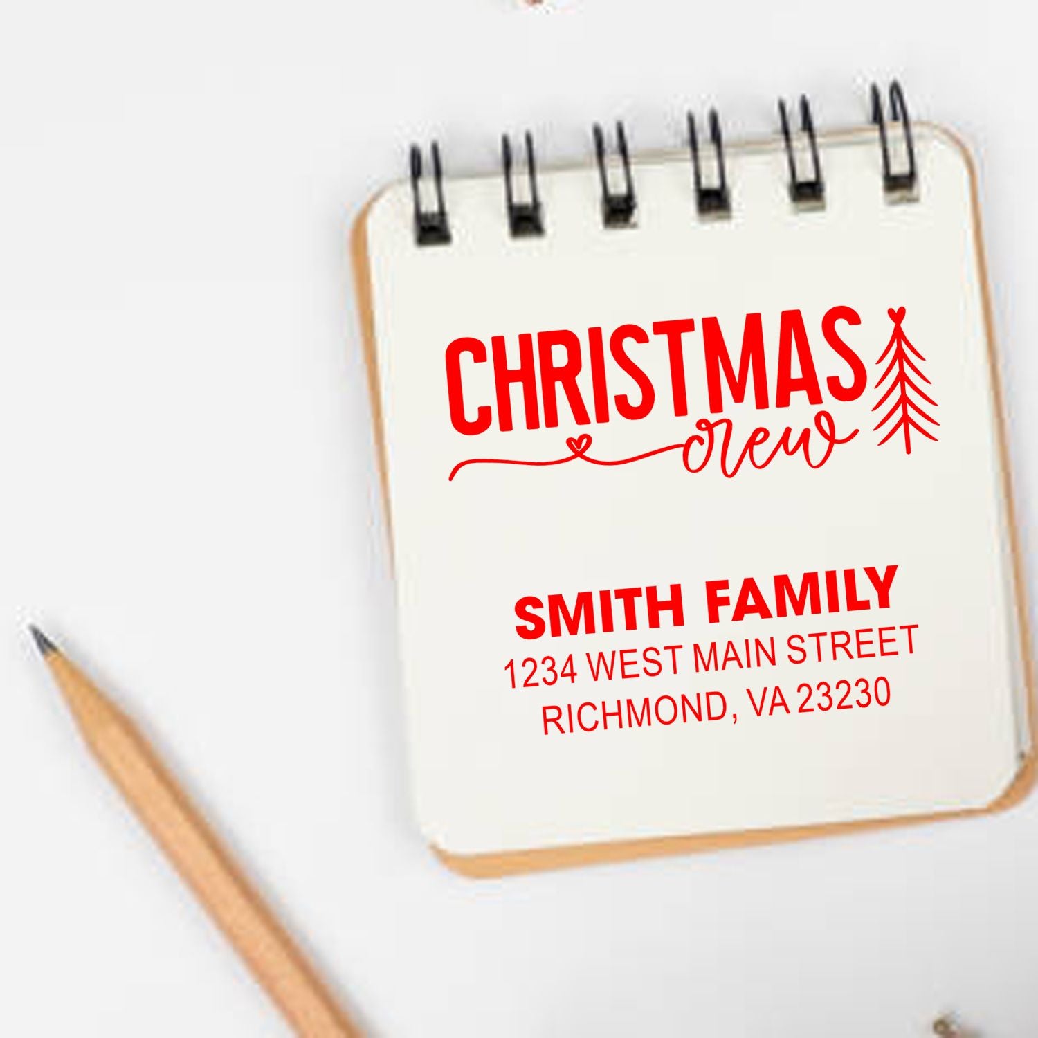 Custom Christmas crew rubber stamp with Smith family return address, shown on a notebook for holiday card addressing.