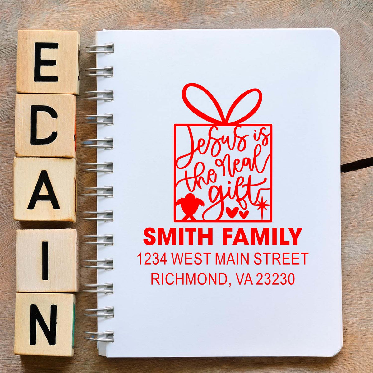 Custom rubber stamp mockup with Jesus is the real gift design and Smith Family return address for holiday cards and gift wrap.