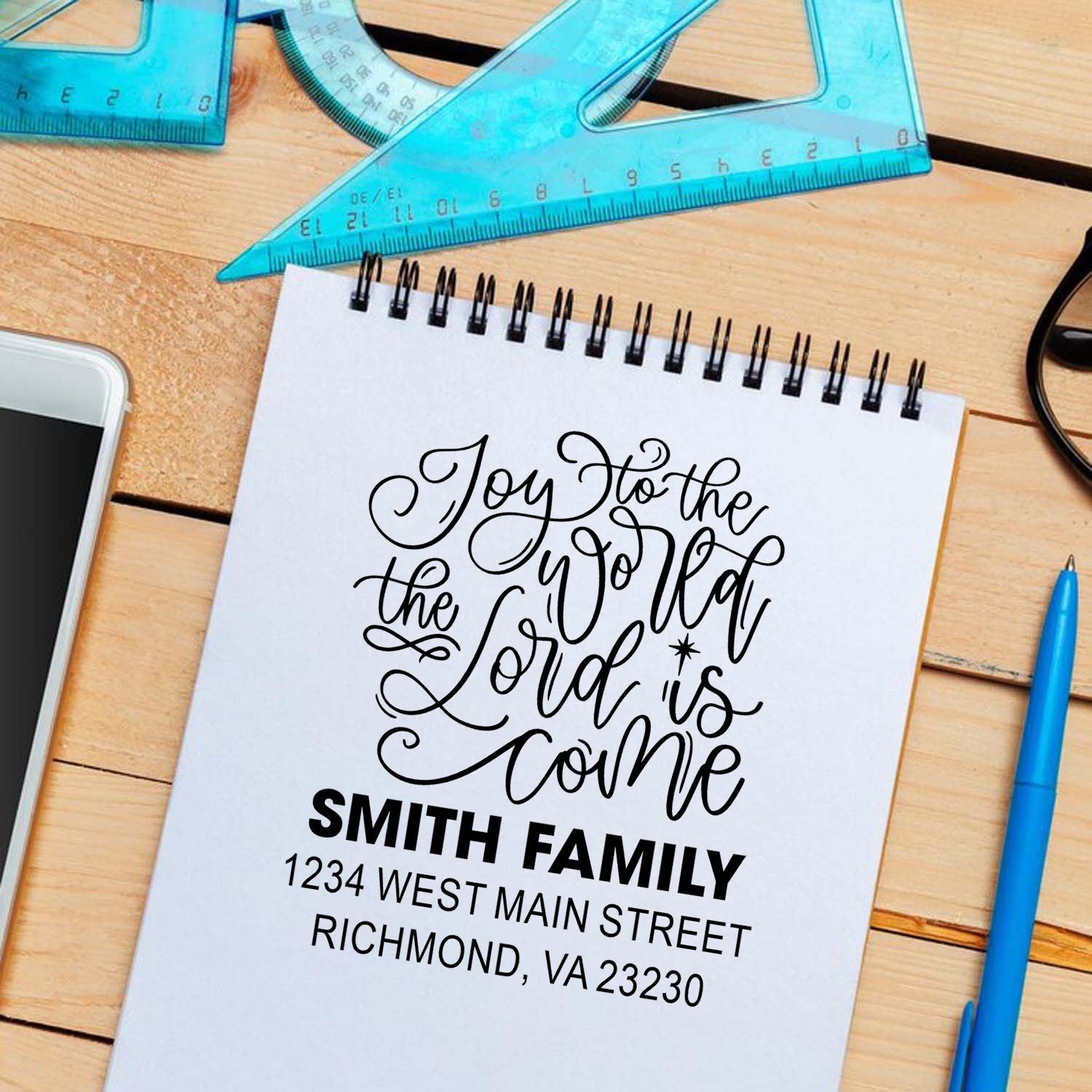 Personalized Christian rubber stamp with family address and Joy to the world design on notebook mockup.