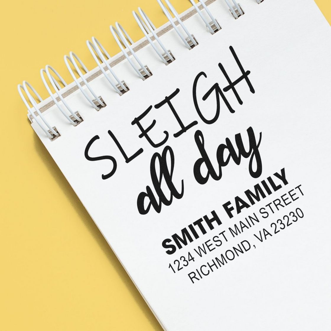 Custom holiday return address rubber stamp with Sleigh all day and Smith family address on a notebook.