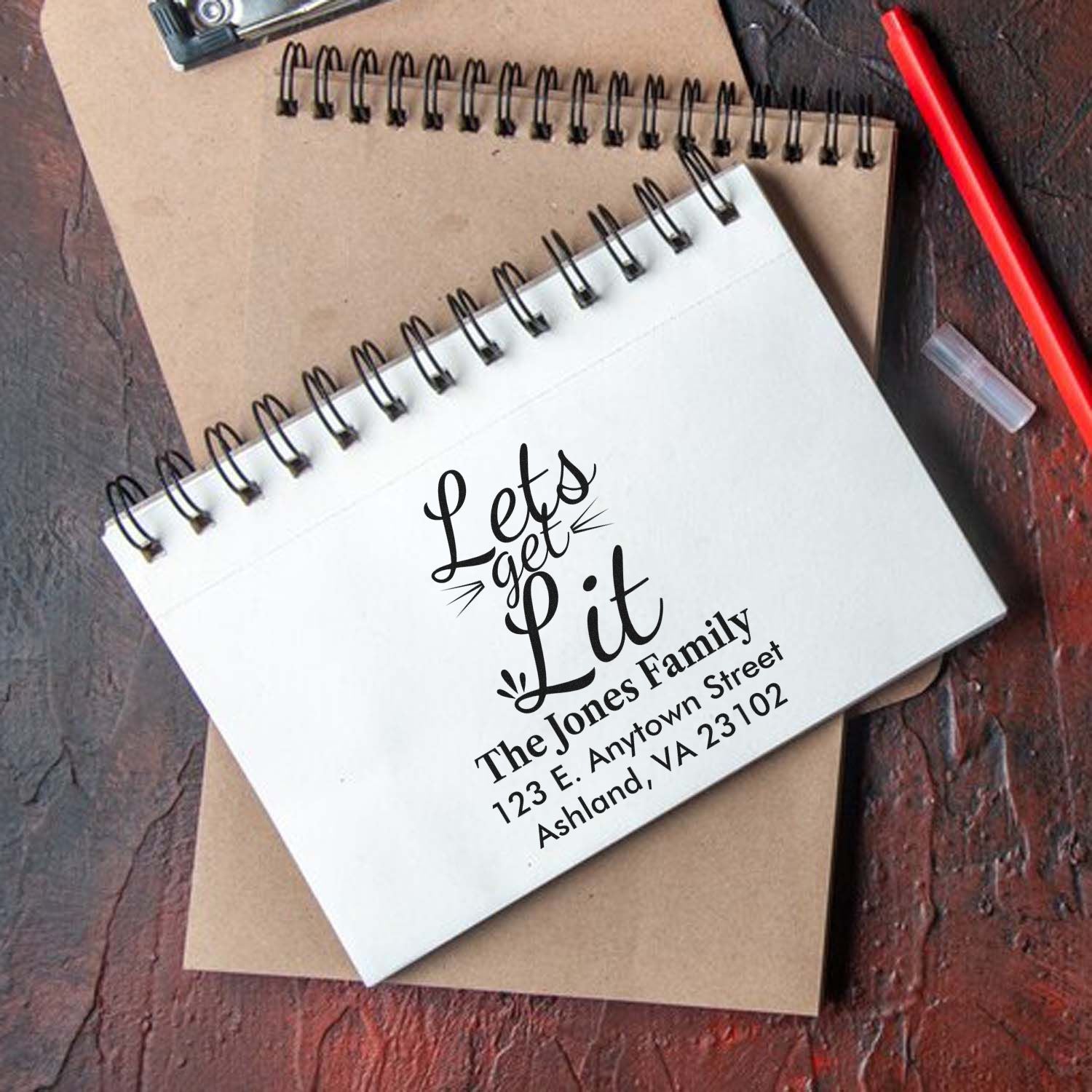 Custom rubber stamp mockup on spiral notebook with Lets get Lit and family address for personalized stationery.