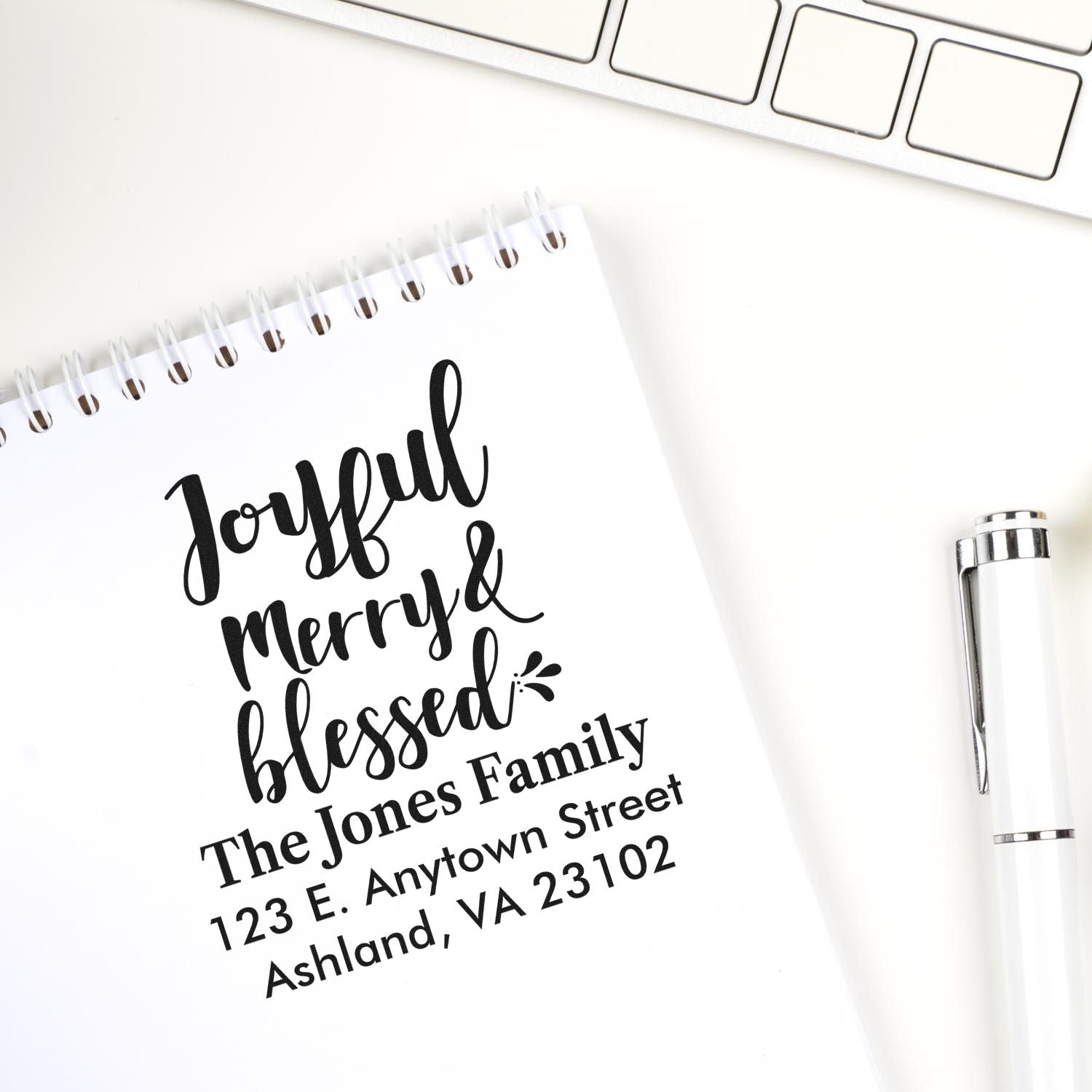 Custom address rubber stamp with Joyful, Merry & Blessed design on notebook, paired with a pen and keyboard.