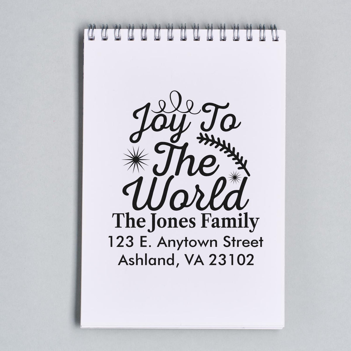 Personalized Joy To The World Christmas return address rubber stamp on a notepad mockup.