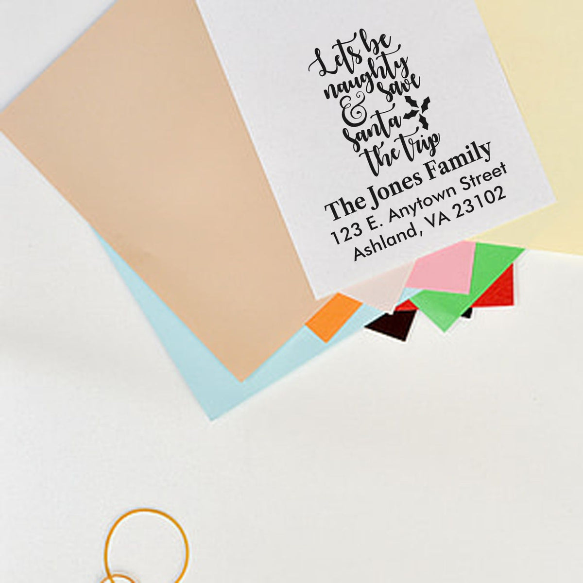 Custom holiday return address rubber stamp on envelope with Lets be naughty Santa design and family address.