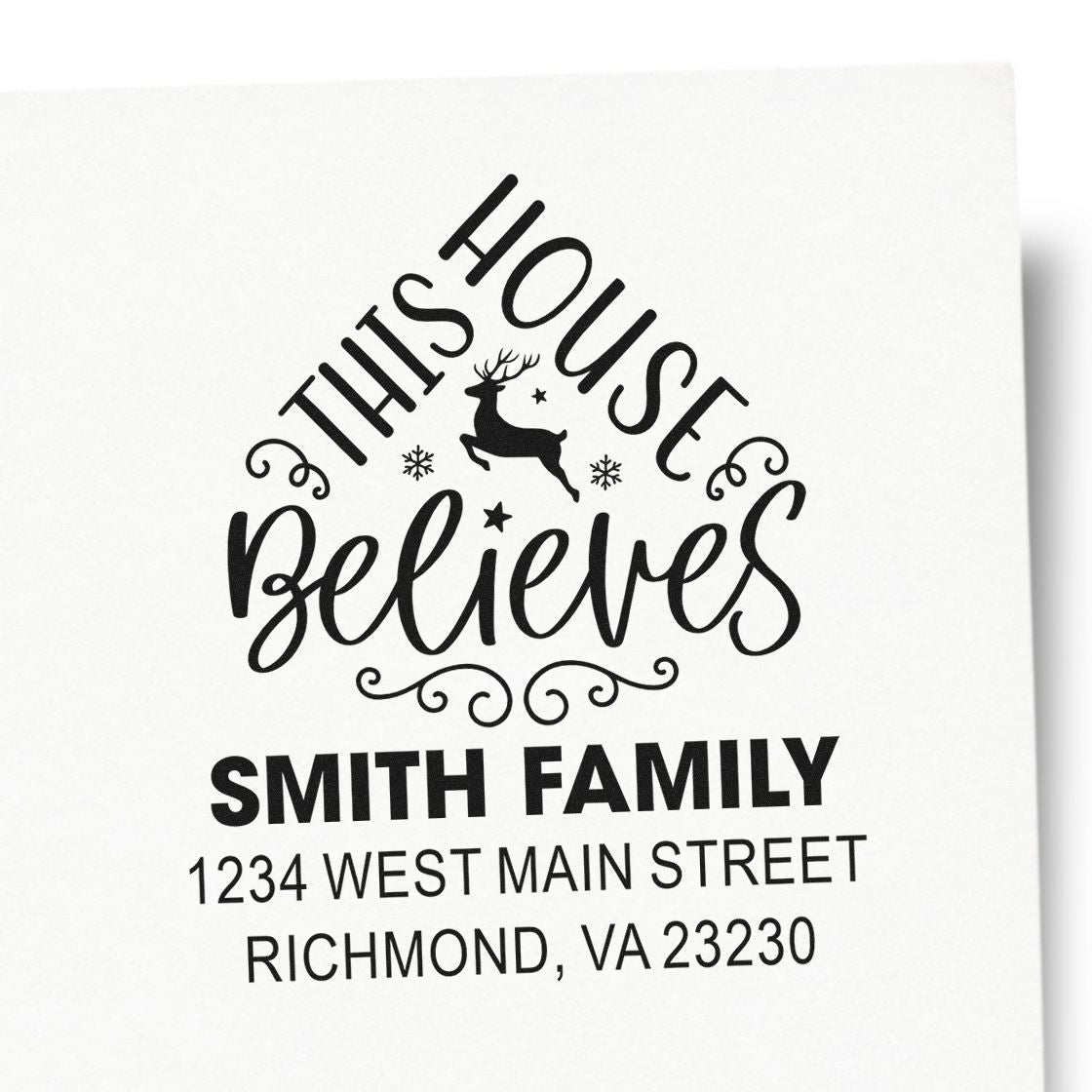 Custom holiday rubber stamp reading This House Believes with family name and address for Christmas cards.