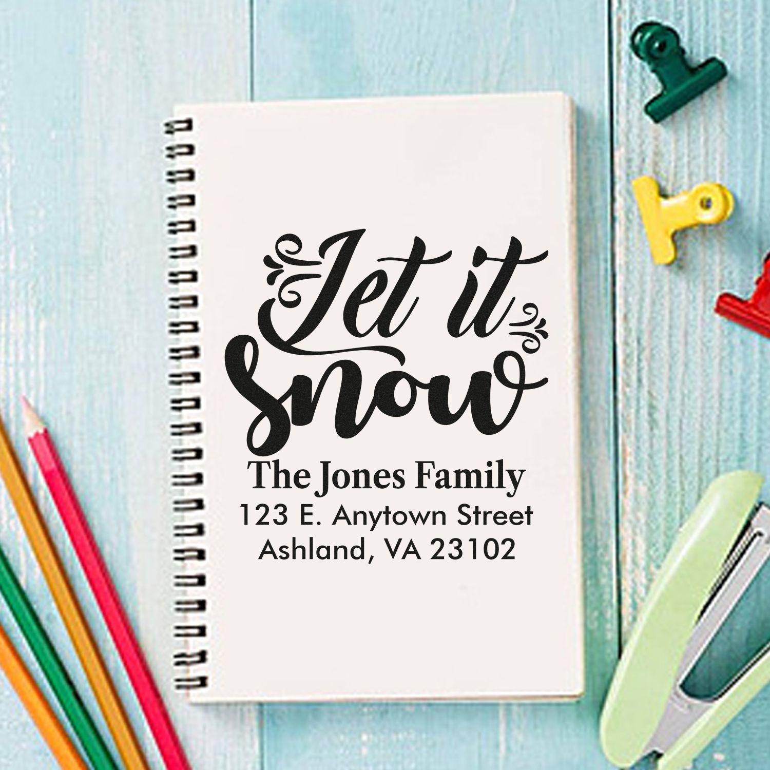 Custom Let it Snow address rubber stamp with family name and mailing address on a notebook.