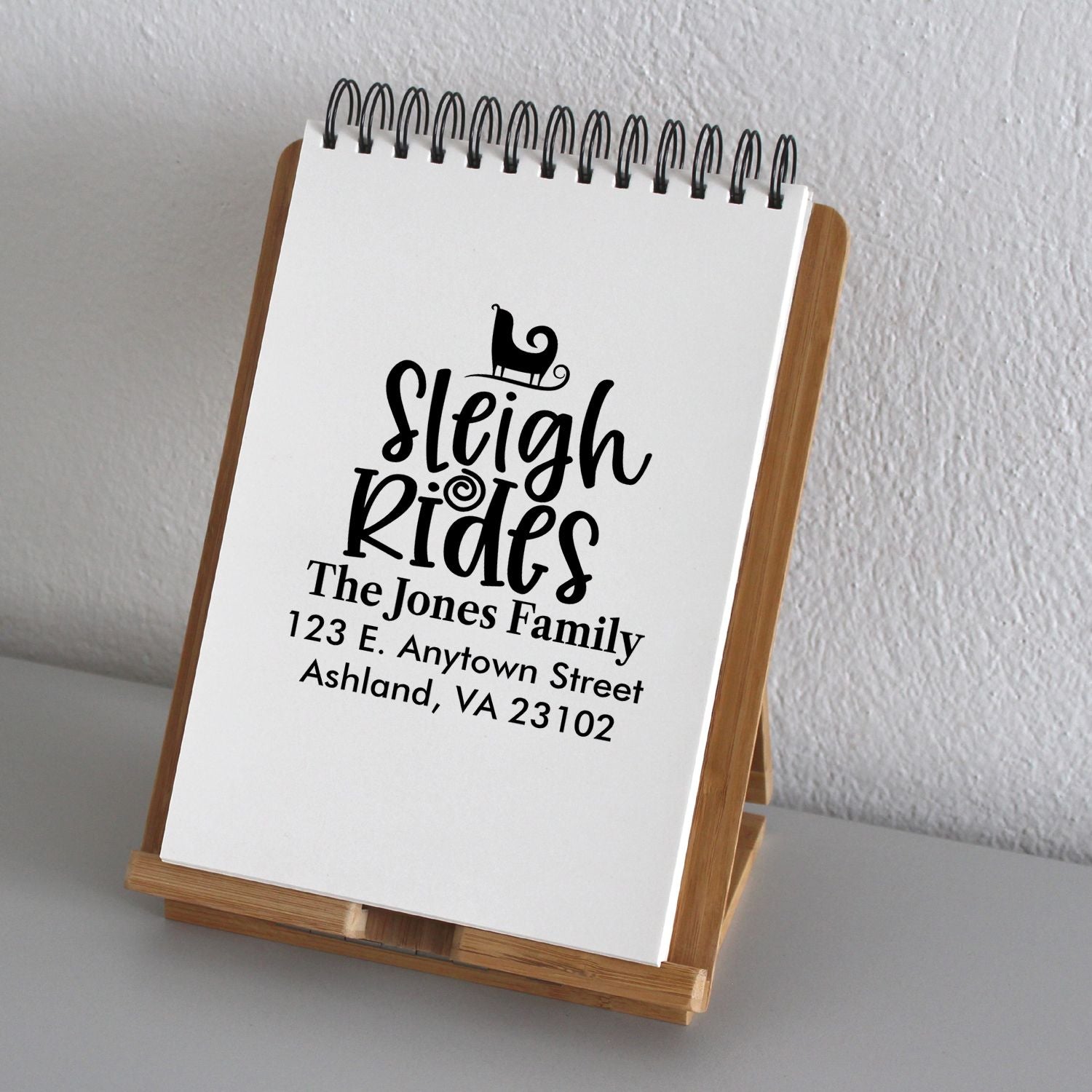 Custom Sleigh Rides address rubber stamp design with family name and mailing address on notepad display.