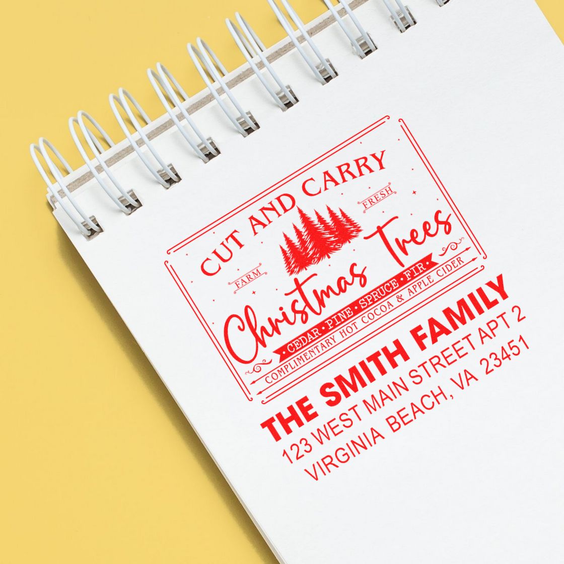 Custom Christmas rubber stamp design with family name and return address on notebook page.