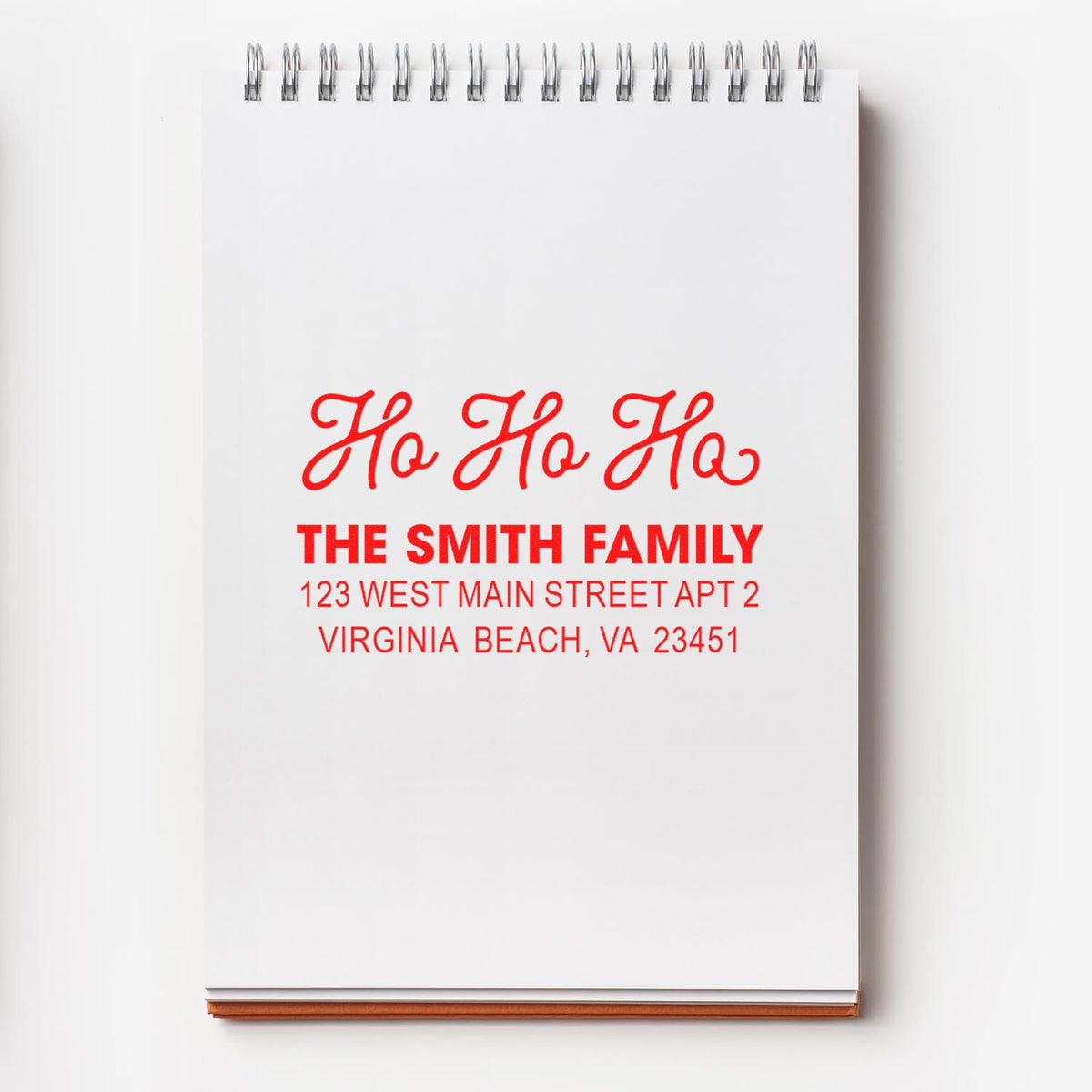 Personalized holiday return address rubber stamp with Ho Ho Ho and The Smith Family address on a notebook page.
