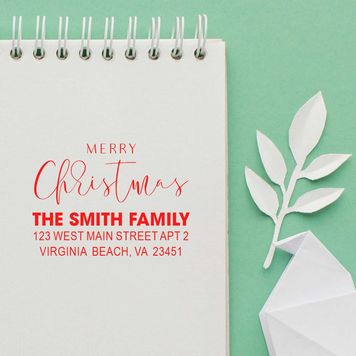 Custom Merry Christmas return address rubber stamp for The Smith Family, shown on a notebook with holiday card design.