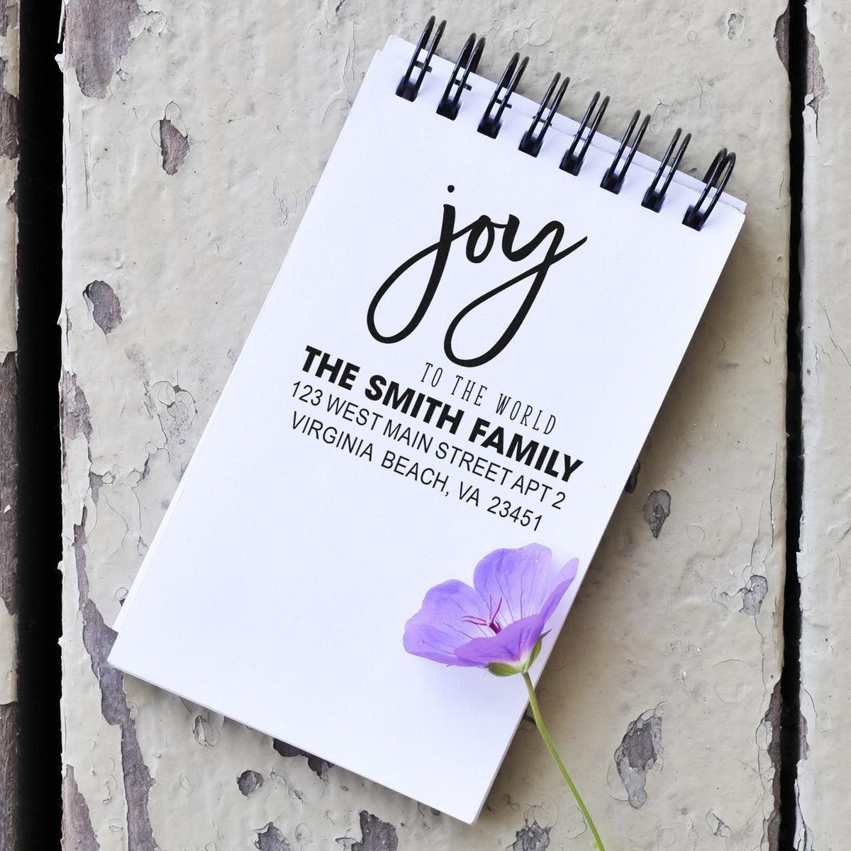 Custom address rubber stamp on a spiral notepad with joy to the world design and flower accent.