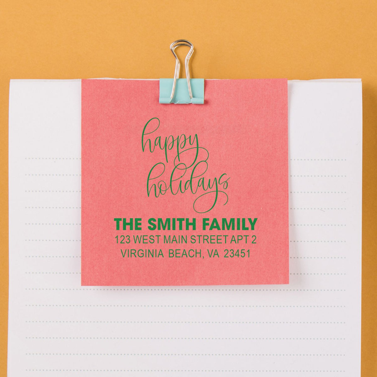 Personalized holiday address rubber stamp with Happy Holidays and Smith Family mailing info on a pink card.