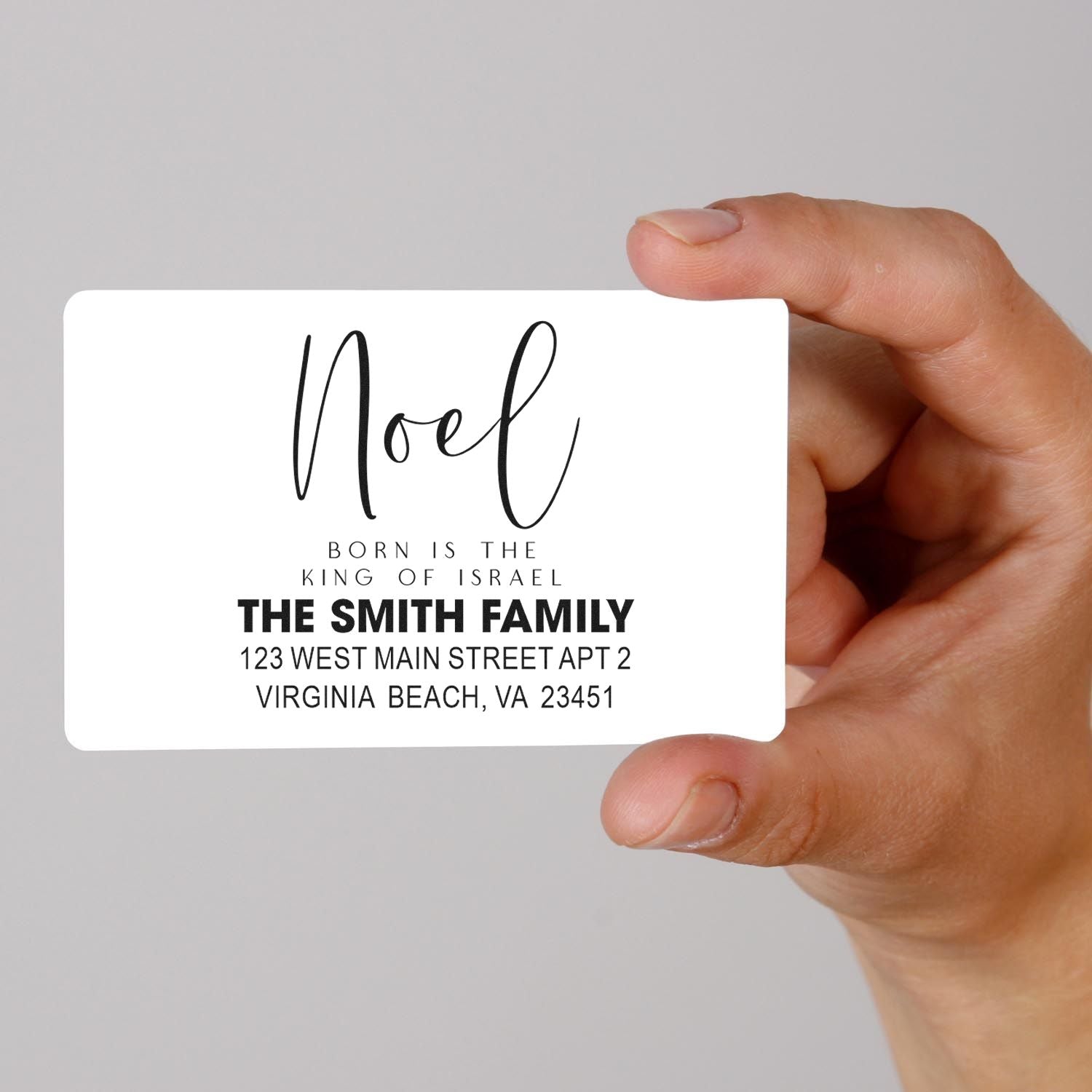 Custom Noel Christmas return address rubber stamp with family name and address, held in hand for holiday mailing.