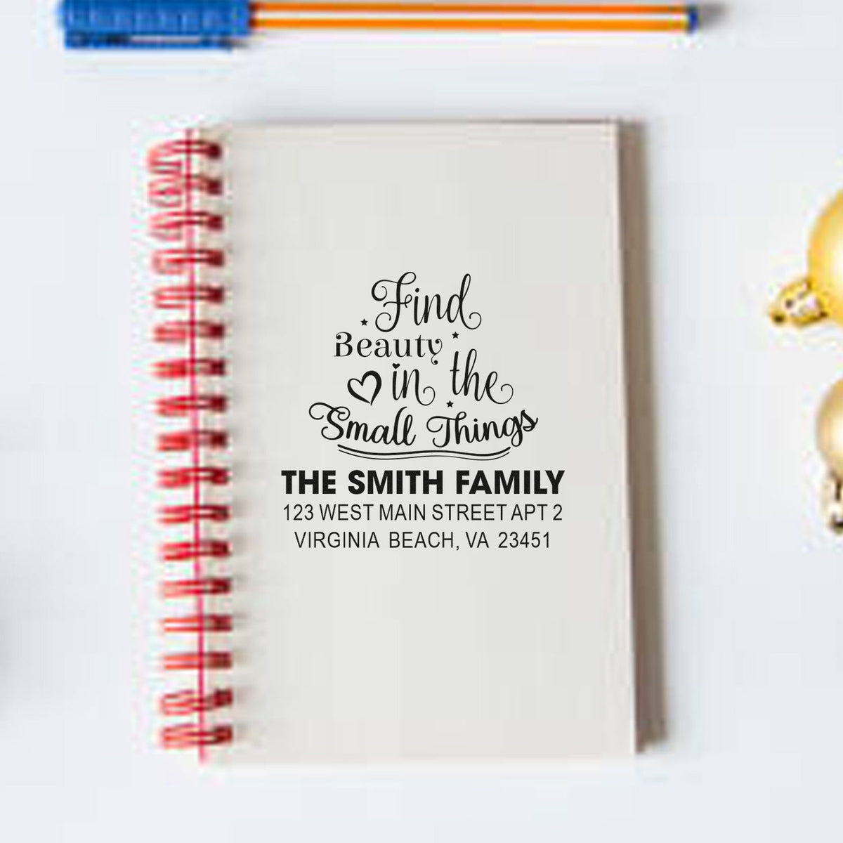 Personalized rubber stamp design on notebook cover with family name and address, featuring Find Beauty in the Small Things.