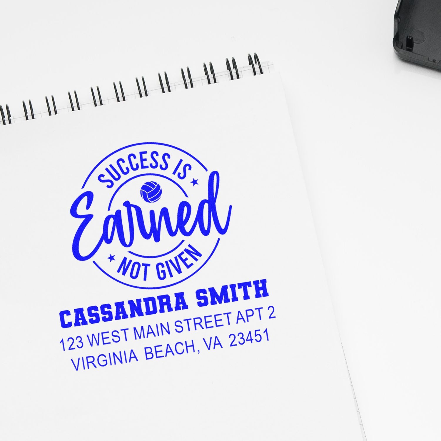 Custom rubber address stamp imprint with Success Is Earned Not Given logo and personalized name and address in blue ink.