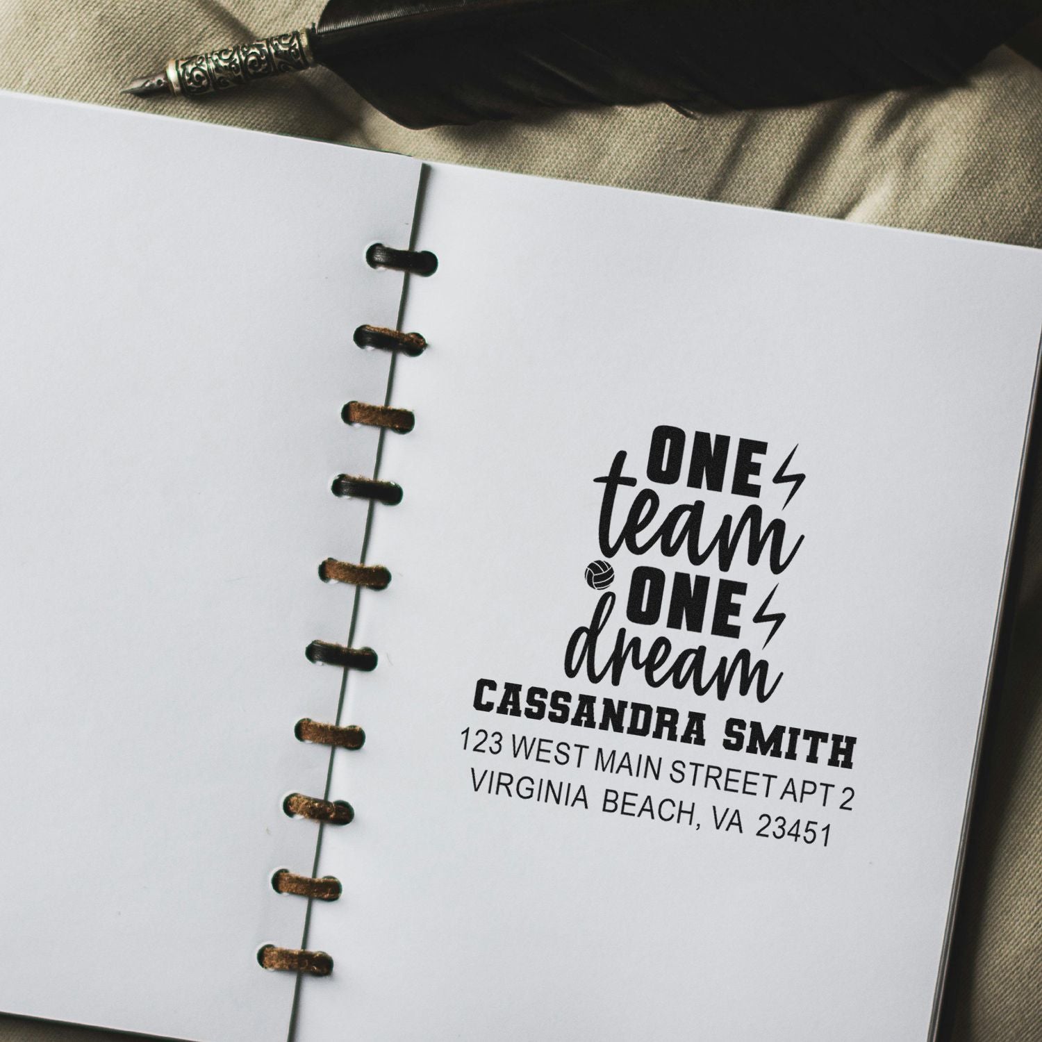 Custom rubber stamp on notebook page with One Team One Dream design, name, and return address for personalized stationery.