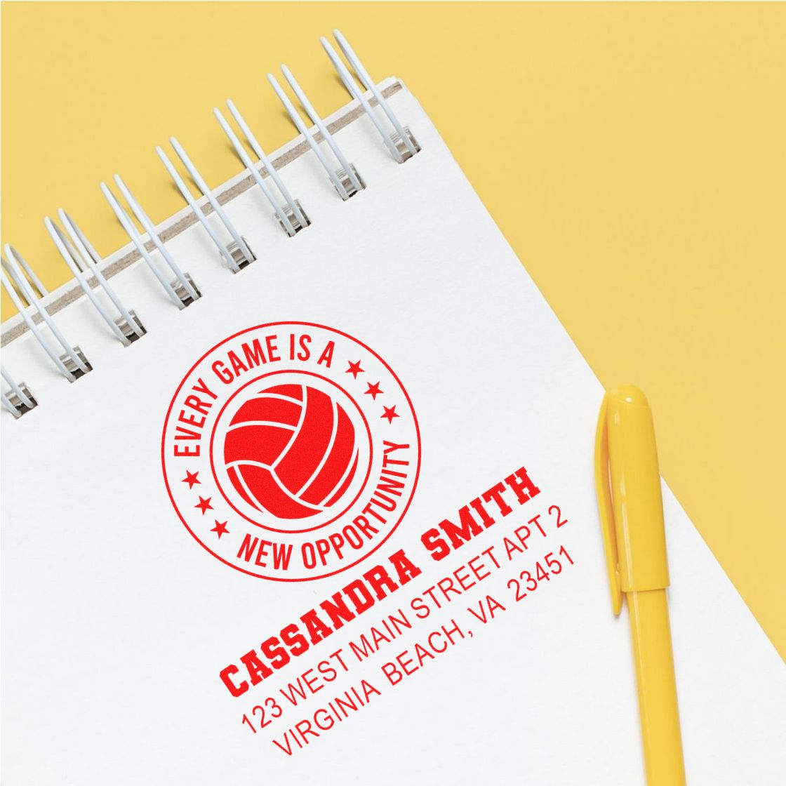 Custom rubber stamp imprint on notebook with volleyball logo, name, and address, showing personalized branding for businesses.